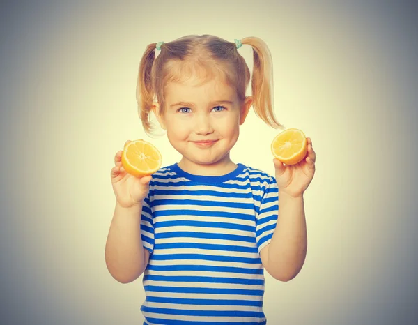 Pequena garota engraçada mantém limões — Fotografia de Stock