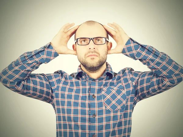 Homme avec des lunettes tenant sa tête avec ses mains . — Photo