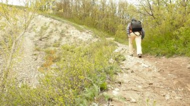 Bir adam orman patikasını yokuş yukarı doğru yürüyor. .