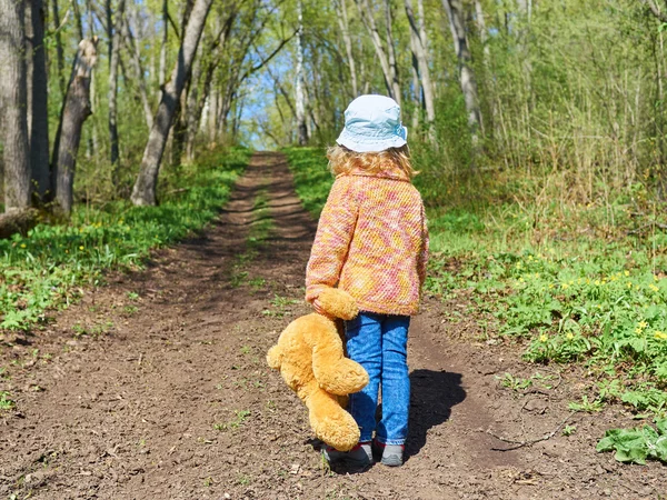 Niño está caminando por el camino con el oso de peluche — Foto de Stock