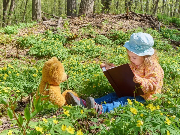 Niedliches Mädchen liest Buch Teddybär — Stockfoto