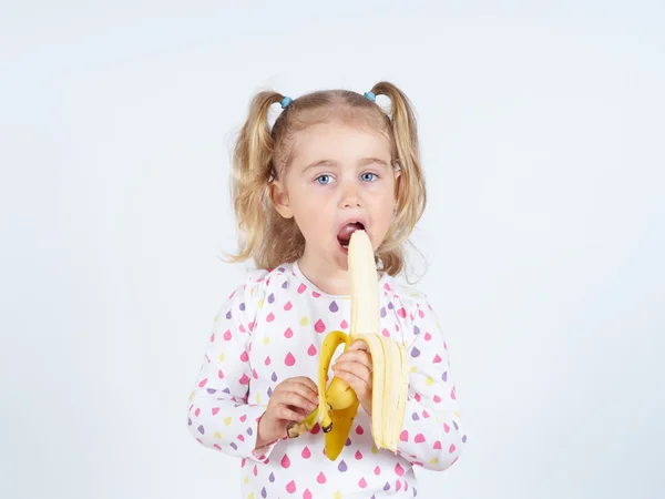 Menina comendo uma banana fresca . — Fotografia de Stock