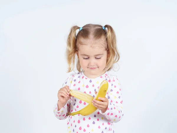 Kleines Mädchen isst eine frische Banane. lizenzfreie Stockbilder