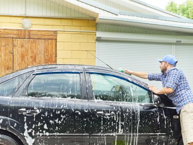 Adam eve yakın onun siyah araba yıkama.