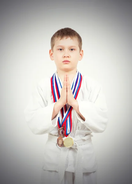 Хлопчик карате в білому кімоно з медалями бійки — стокове фото