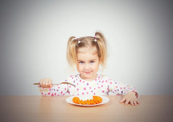 Kislány eszik sárgarépa villával. — Stock Fotó