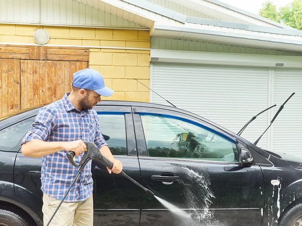 Hombre lavando su coche negro cerca de casa . — Foto de Stock