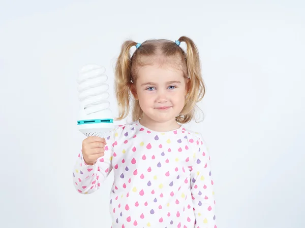 Menina mostra um grande lâmpadas economizadoras de energia . — Fotografia de Stock