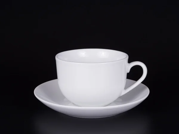 White cup on a saucer isolated on a black background — Stock Photo, Image