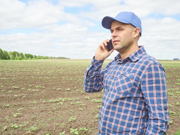 El granjero en una camisa a cuadros controlaba su campo.Hablando por teléfono . — Foto de Stock