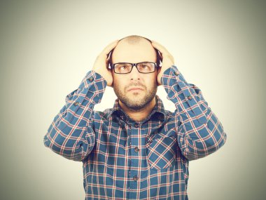 Başını elleri ile tutarak gözlüklü adam.