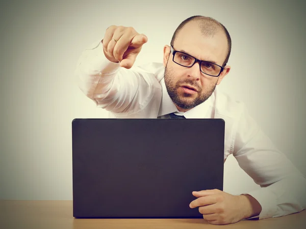 Angry  businessman sitting at his desk Stock Photo