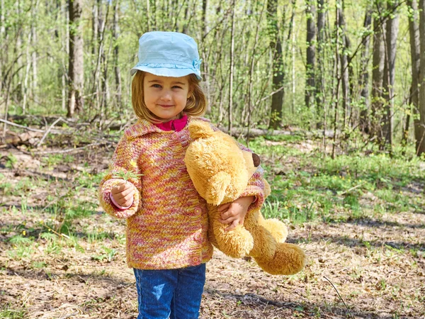 Meisje met teddybeer geeft gele bloem. — Stockfoto