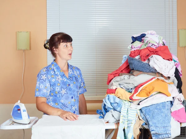 Young Caucasian woman ironed clothes in the room near  window.