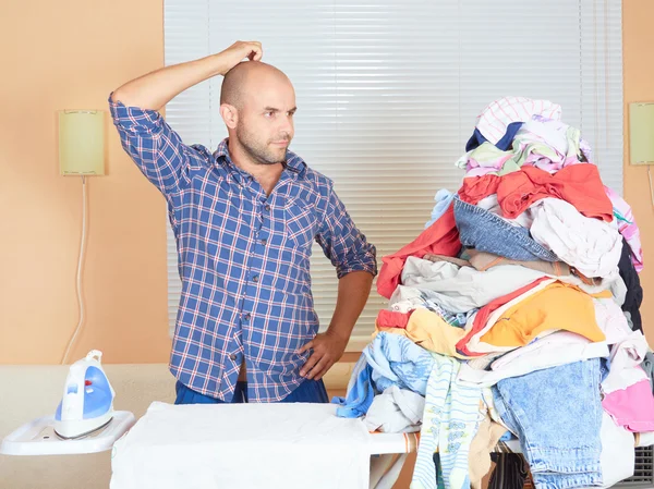 Caucasian man ironed clothes in the room near the window.