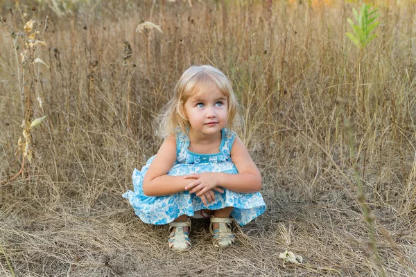 Liten flicka sitter i gräset — Stockfoto