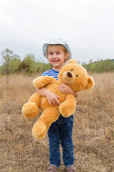 Bonito menina abraçando um grande ursinho de peluche — Fotografia de Stock