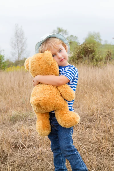 Söt liten flicka kramar en stor nallebjörn — Stockfoto