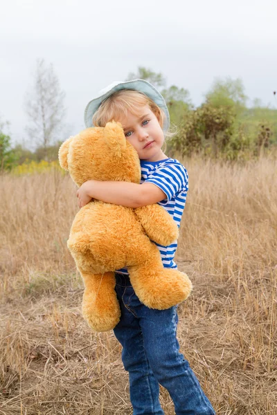 Linda niña abrazando a un gran oso de peluche — Foto de Stock