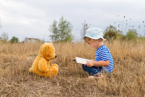 Niedliches Mädchen liest Buch Teddybär — Stockfoto