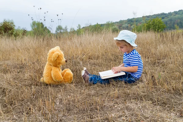 Милая девушка читает книгу Тедди Медведь — стоковое фото