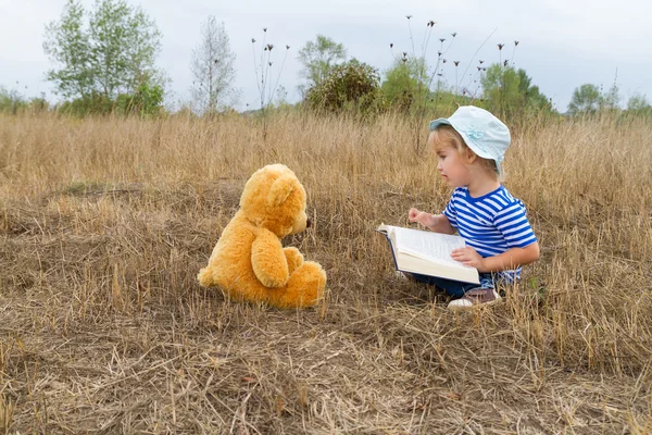 Niedliches Mädchen liest Buch Teddybär — Stockfoto