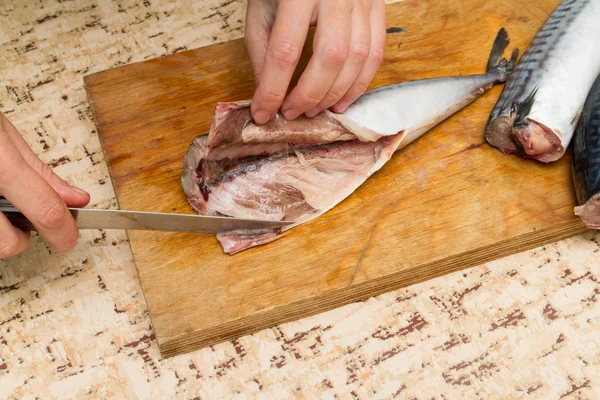 Een vrouw chef-kok segmenten een makreel vissen op een houten bord — Stockfoto