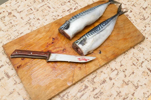 Женщина-повар режет рыбную скумбрию на деревянной доске — стоковое фото