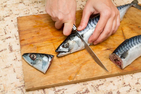 Uma mulher chef corta um barril de peixe em uma tábua de madeira — Fotografia de Stock