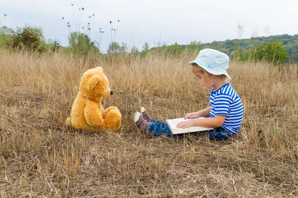 Linda chica leyendo libro osito de peluche —  Fotos de Stock