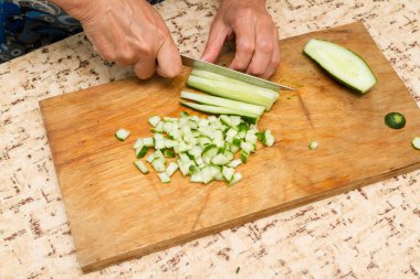 The chef cuts the cucumber on a wooden  Board. clipart