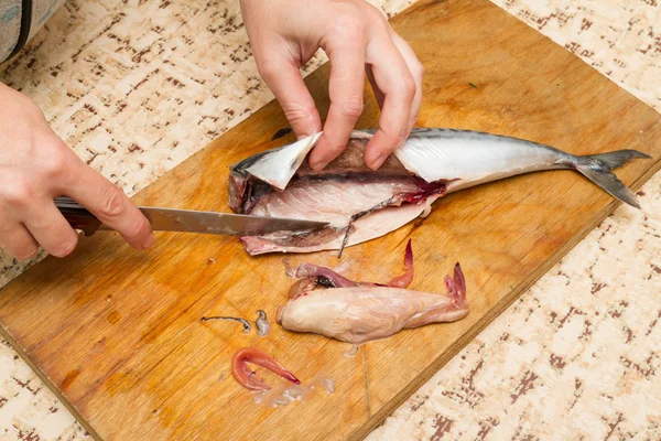 Uma mulher chef corta um barril de peixe em uma tábua de madeira — Fotografia de Stock