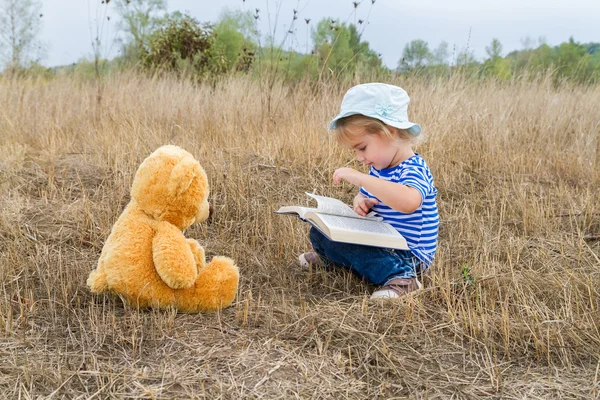 Söt flicka läsa bok Nalle — Stockfoto