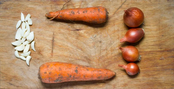 Cipolle, aglio e carote su un tavolo di legno rustico . — Foto Stock
