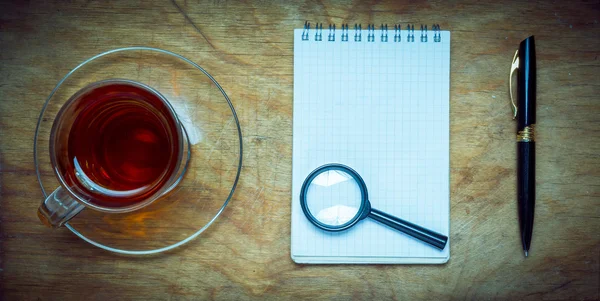 Small notebook with a Cup of tea, stick on a rustic wood backgro