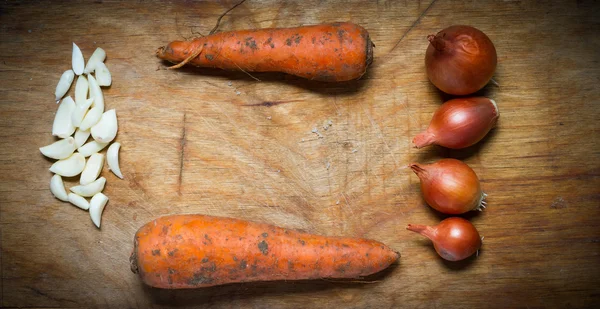 Cipolle, aglio e carote su un tavolo di legno rustico . — Foto Stock