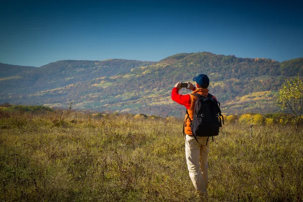 Turista masculino com mochila tirando fotos de paisagens para o seu s — Fotografia de Stock