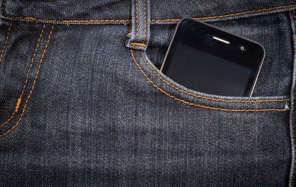 Black smartphone in your pocket jeans. background.