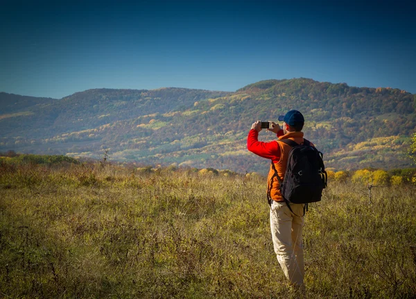 Turista masculino con mochila tomando fotos de paisajes a su s —  Fotos de Stock