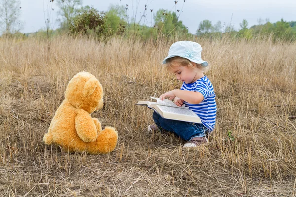 Leuk meisje lezen boek Teddy bear — Stockfoto