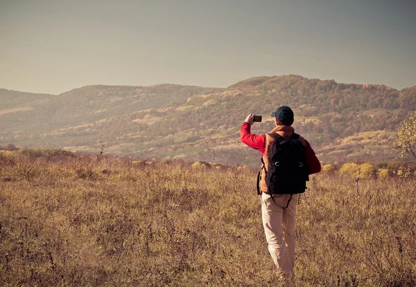 Turista masculino com mochila tirando fotos de paisagens para o seu s — Fotografia de Stock