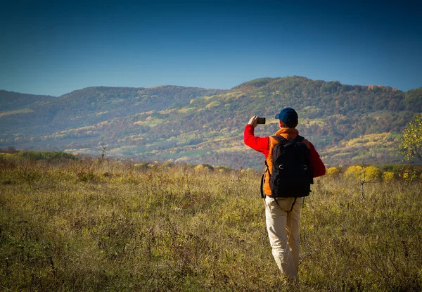 Turista masculino com mochila tirando fotos de paisagens para o seu s — Fotografia de Stock