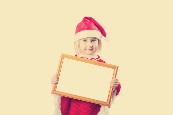 Niña con sombrero Santa Claus sosteniendo el marco con un fondo blanco —  Fotos de Stock