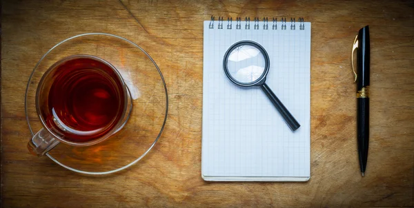 Mały notatnik z filiżanką herbaty, trzymać na rustykalne backgro drewna — Zdjęcie stockowe