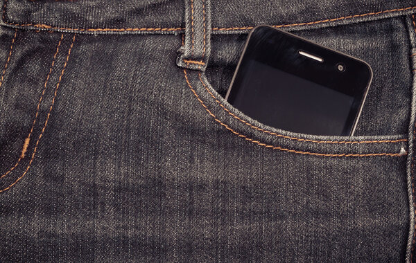 Black smartphone in your pocket jeans. background.