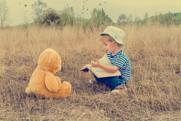 Leuk meisje lezen boek Teddy bear — Stockfoto