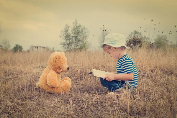 Niedliches Mädchen liest Buch Teddybär — Stockfoto