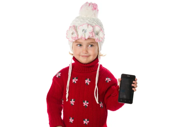 Meleg sapka és egy piros pulóver kislány azt mutatja, smartphone — Stock Fotó