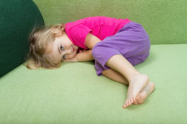 Klein meisje liggend op de Bank. — Stockfoto