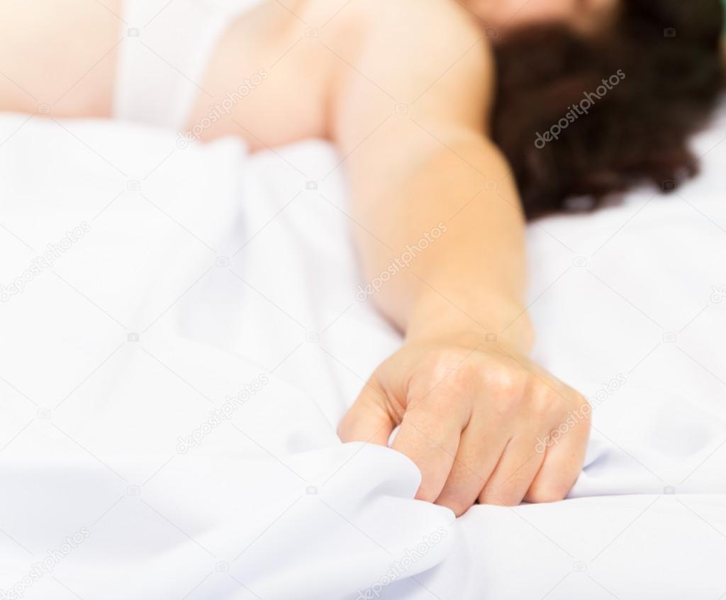 Female hand pulling white sheets in ecstasy